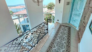 A staircase with ornate metal railings, a patterned floor, a blue door, and a view of the neighborhood. - Rüzgar Gülü Otel (Cesme)