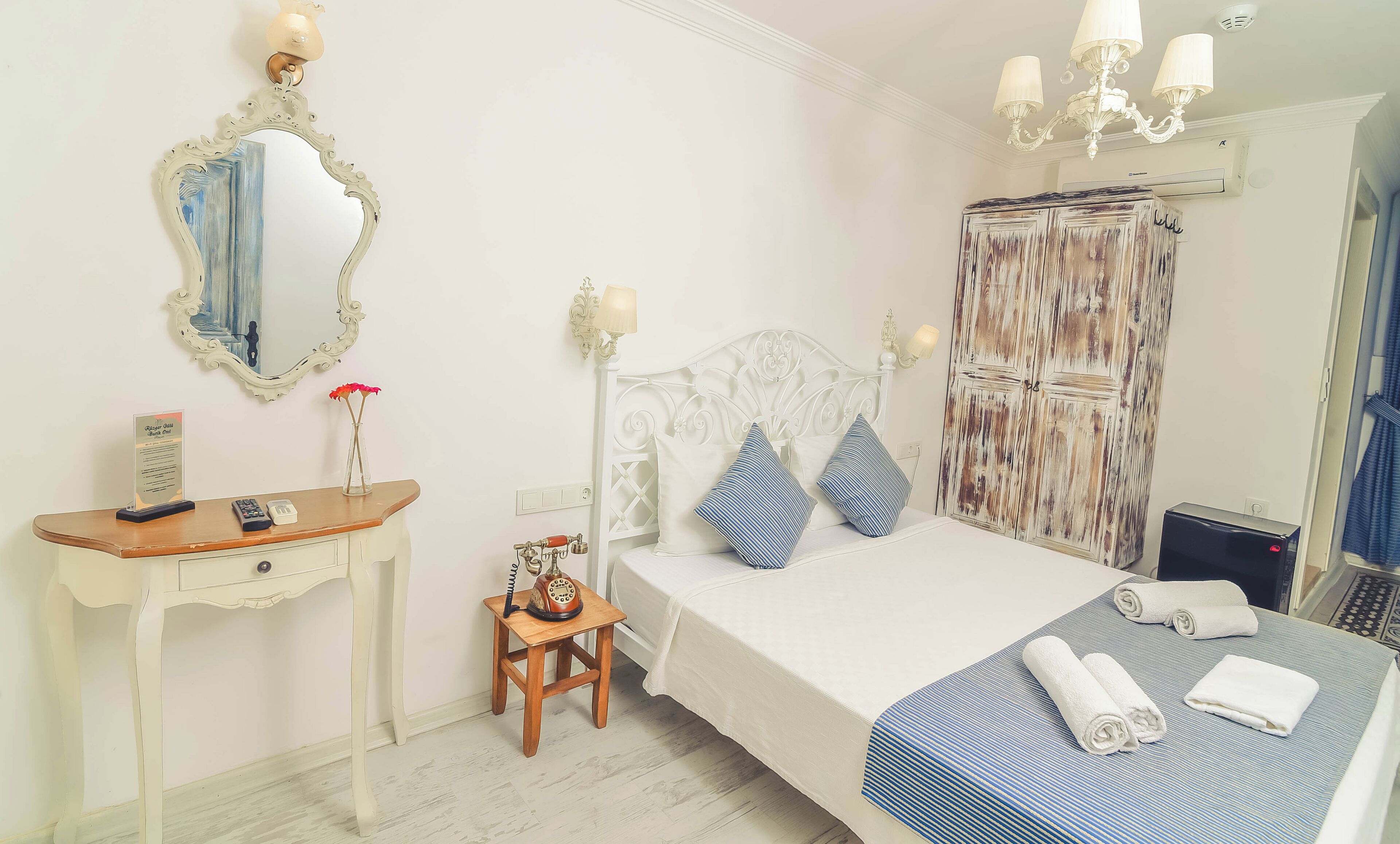 A hotel room with a bed, bedside table, vanity, and a wardrobe.