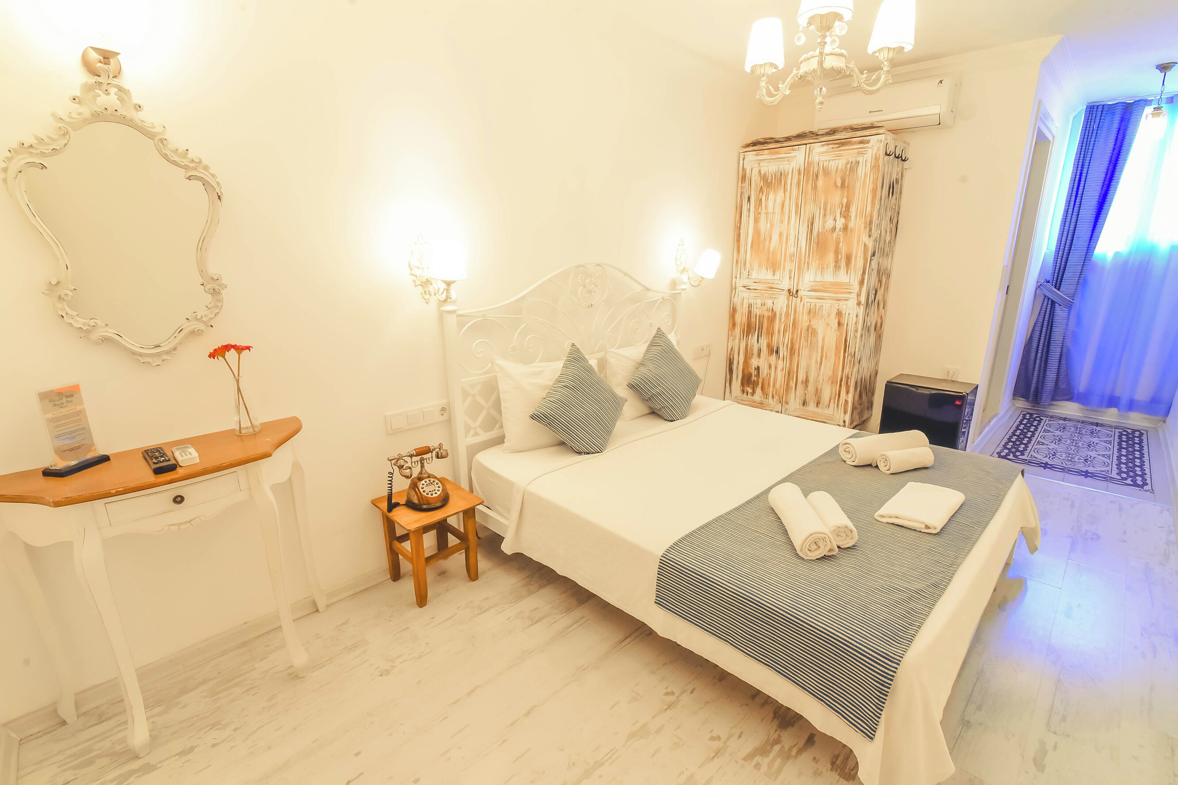 Une chambre à coucher bien rangée, avec un lit, une table de chevet, une lampe et un miroir.
