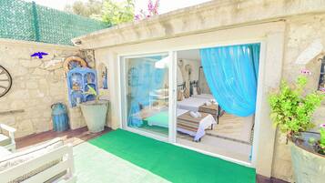 Una habitación con una cama, una ventana con cortinas azules, una mesita pequeña y una silla.