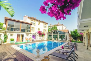 A swimming pool area with lounge chairs and a sun deck. - Rüzgar Gülü Otel (Cesme)