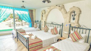 A hotel room with two beds, a balcony, and a stone archway. - Rüzgar Gülü Otel (Cesme)