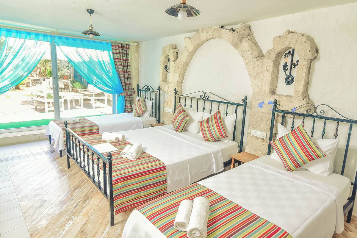 A hotel room with two beds, a balcony, and a stone archway.
