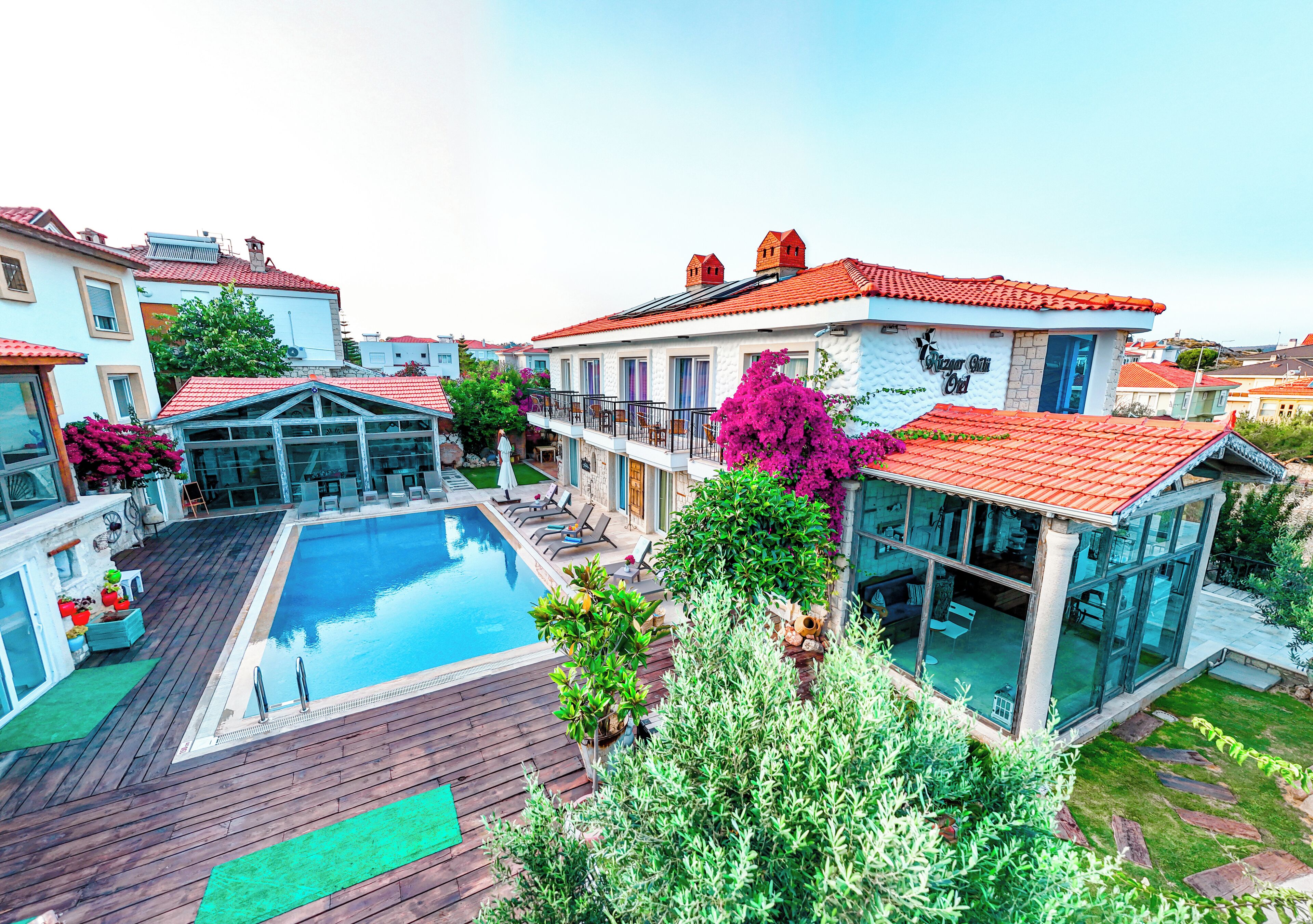 Um imóvel residencial com piscina, solário envidraçado e telhado de telhas vermelhas.