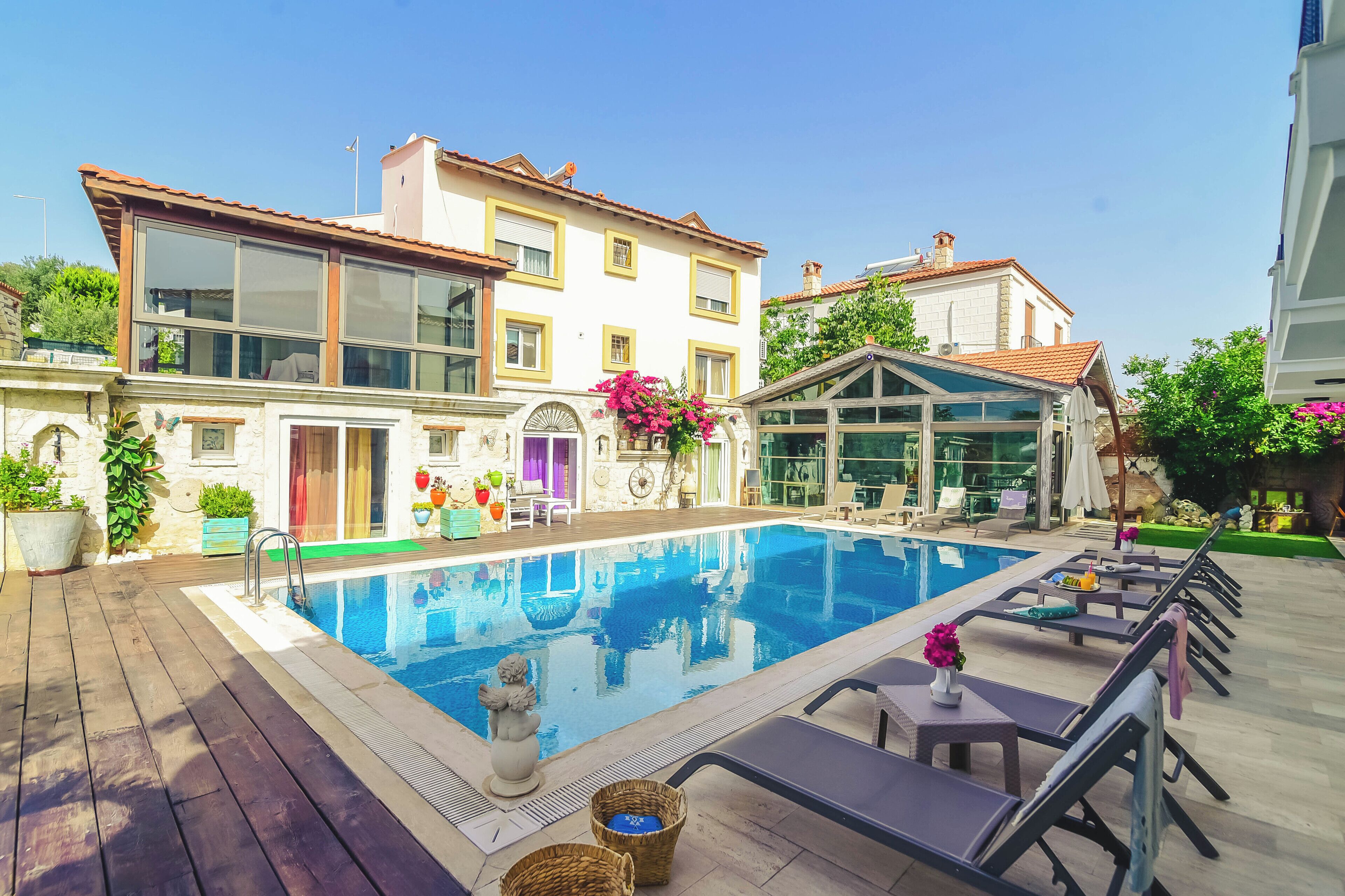 A swimming pool with lounge chairs and a building with large windows and a tiled roof.