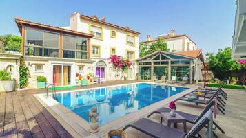 Una piscina al aire libre, sombrillas, sillones reclinables de piscina