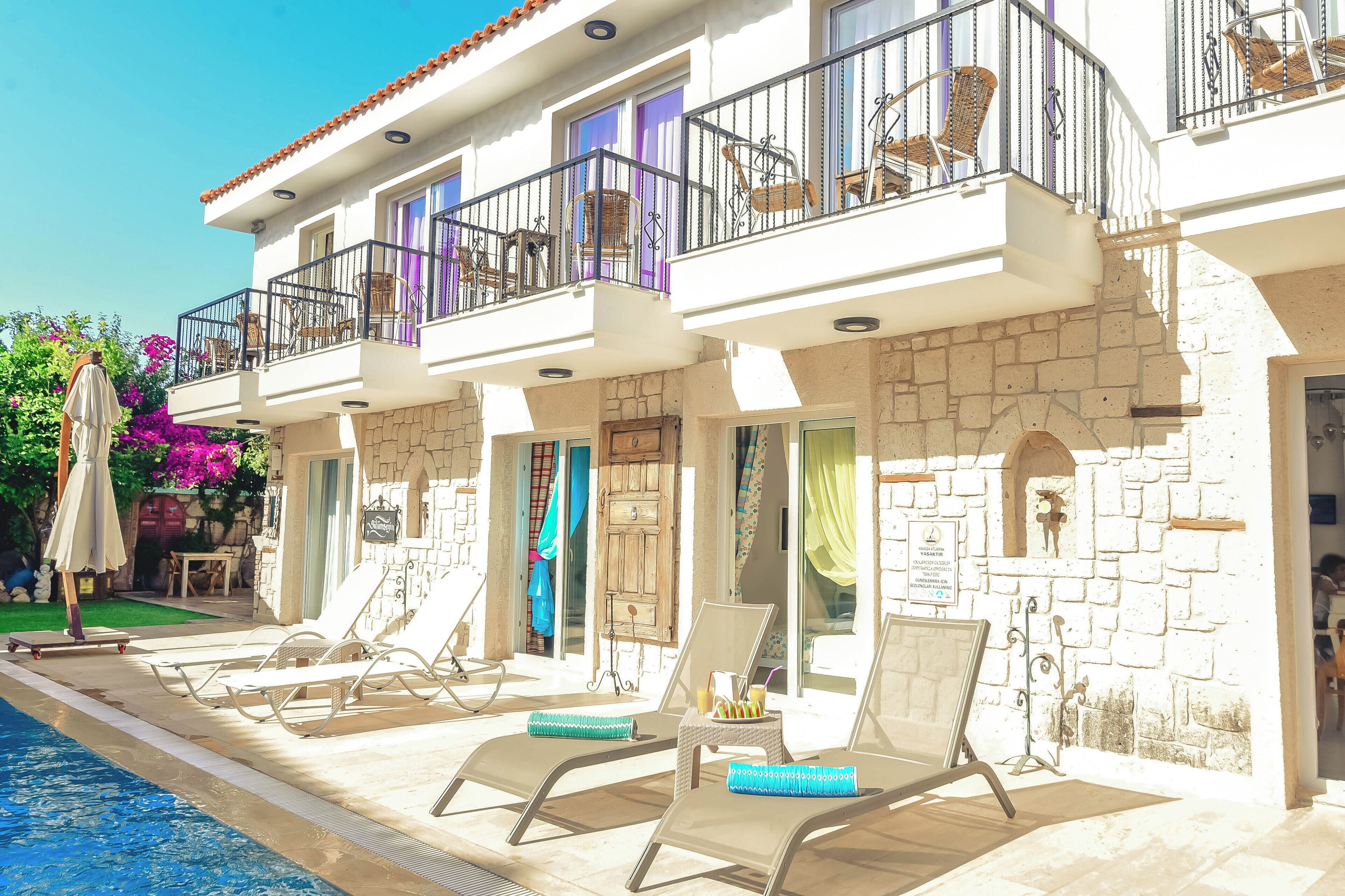 A hotel with a pool area, lounge chairs, and a stone facade.