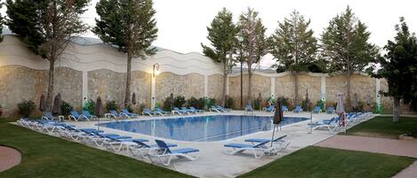 Piscina con sillas de descanso y un muro de piedra.