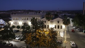 A large, historic building with multiple windows and a central courtyard, surrounded by parked cars and trees. - Hotel El Carmen (Puente Genil)
