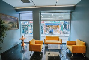 Un vestíbulo con un ventanal grande, dos sillones amarillos, una mesita y un objeto decorativo de cobre.