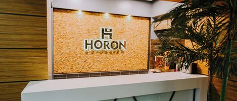 A reception desk with a textured wall and the name "HORON" displayed prominently.