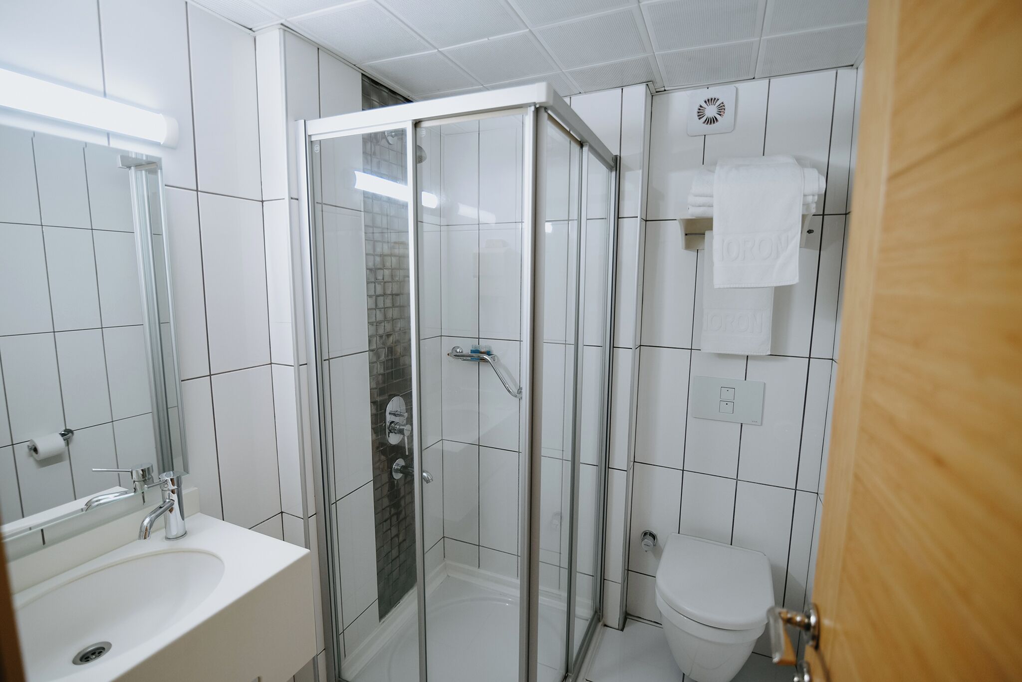 Une salle de bain moderne avec une douche à parois de verre, un lavabo blanc et des toilettes.