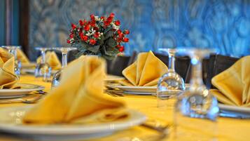A dining table set with yellow napkins, clear glassware, and a centerpiece of red roses.