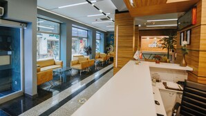 A modern reception area with a white counter, wooden accents, and a seating area with yellow chairs. - Horon Hotel (Trabzon)