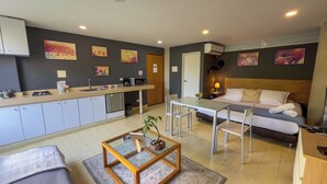 Een compacte leefruimte met een kitchenette, een eethoek, een bank en een bed.