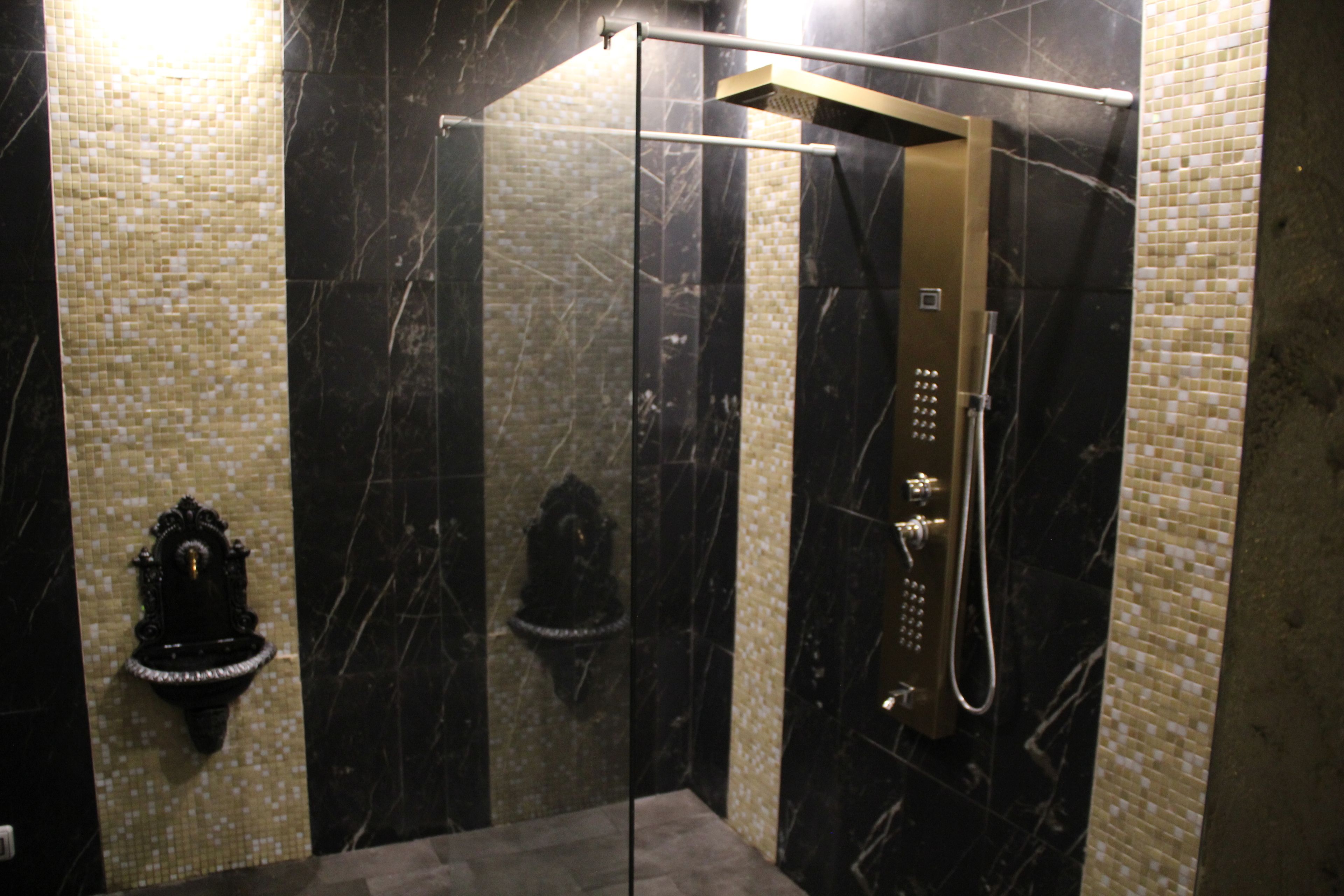 A modern bathroom with a glass-enclosed shower, a handheld showerhead, and a wall-mounted faucet.