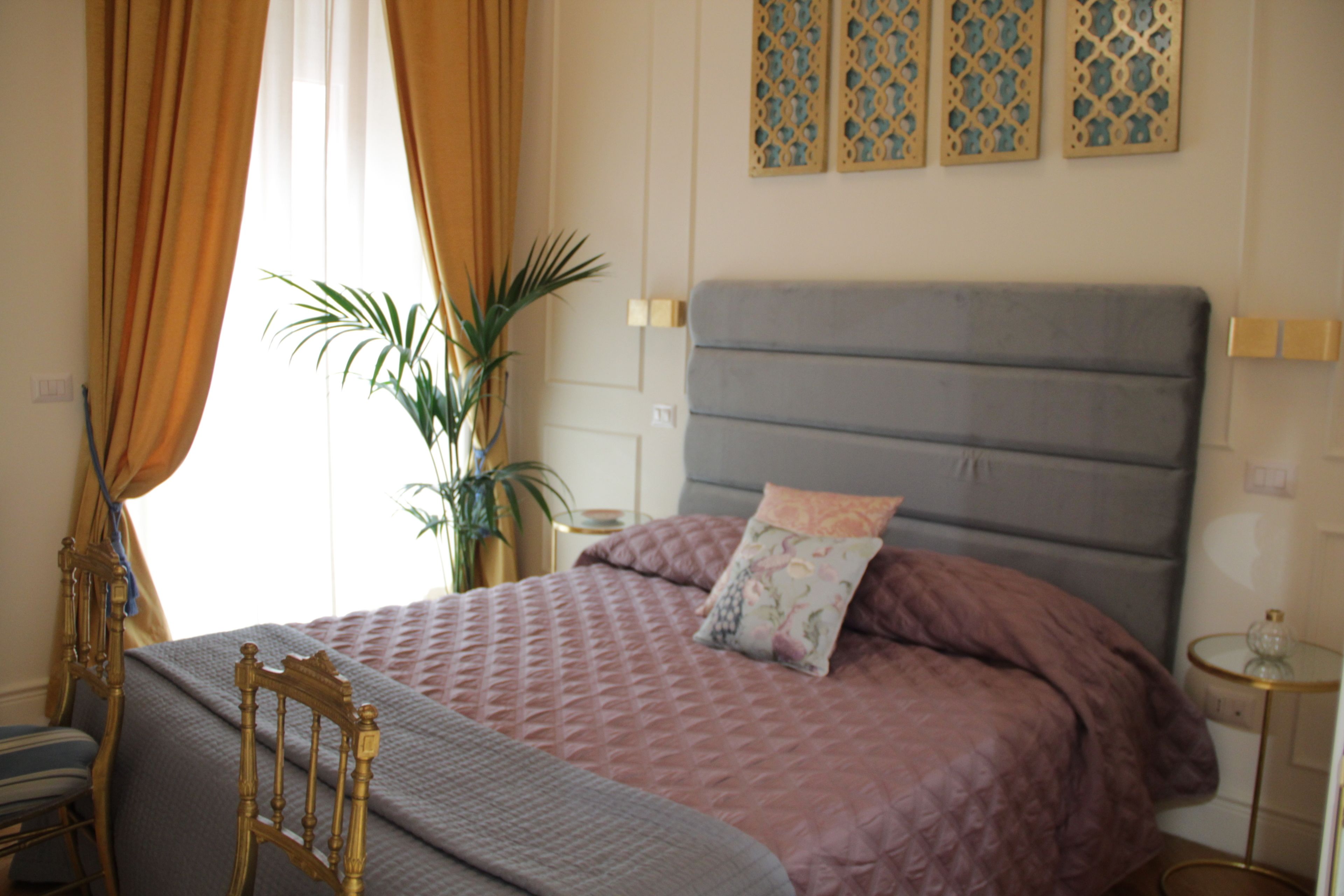 Una camera da letto con un letto, tende, una pianta e pannelli decorativi a parete.
