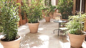 An outdoor patio with potted plants, a round table, and chairs. - Ingrami Suites (Rome)