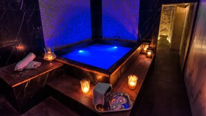 A spa room with a hot tub, candles, and a tray with bath items. - Ingrami Suites (Rome)