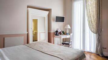A hotel room with a bed, a desk, a chair, a TV, and a window with curtains.