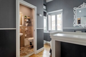Un bagno moderno con doccia, servizi igienici e lavandino, dotato di un ampio specchio e vista esterna.