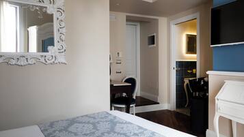 Une chambre d’hôtel avec un lit, un miroir, une télévision, un bureau et une chaise.