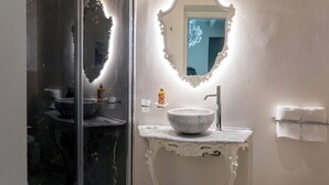 A bathroom with a marble sink, a white ornate mirror, and a towel rack. - Dimora Bellini residenza d' epoca (Palermo)