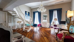 A spacious room with a wooden floor, a white staircase, a chandelier, and a large mirror. - Dimora Bellini residenza d' epoca (Palermo)