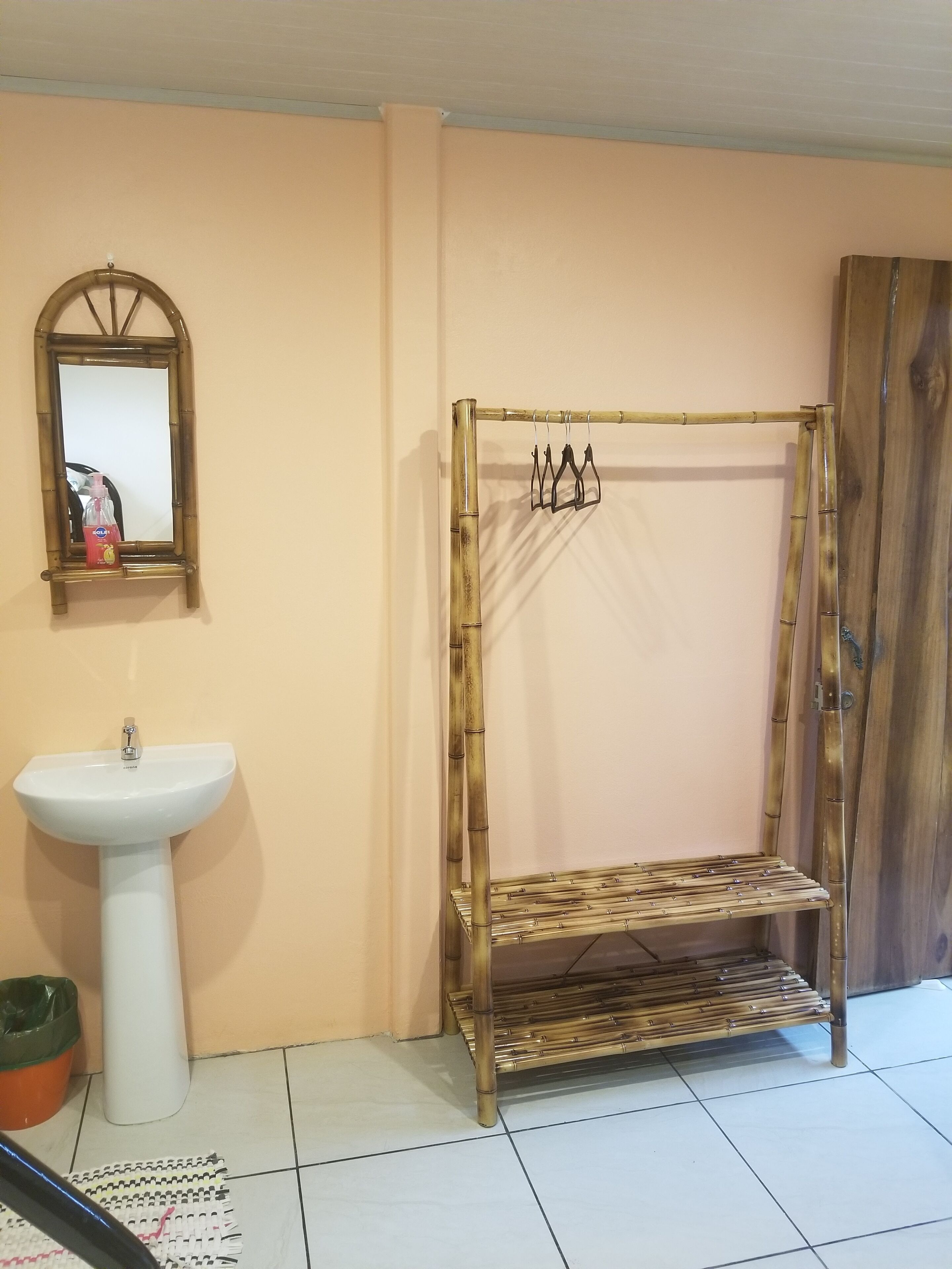 Un baño con cabina de ducha de bambú, un lavabo blanco y un espejo.