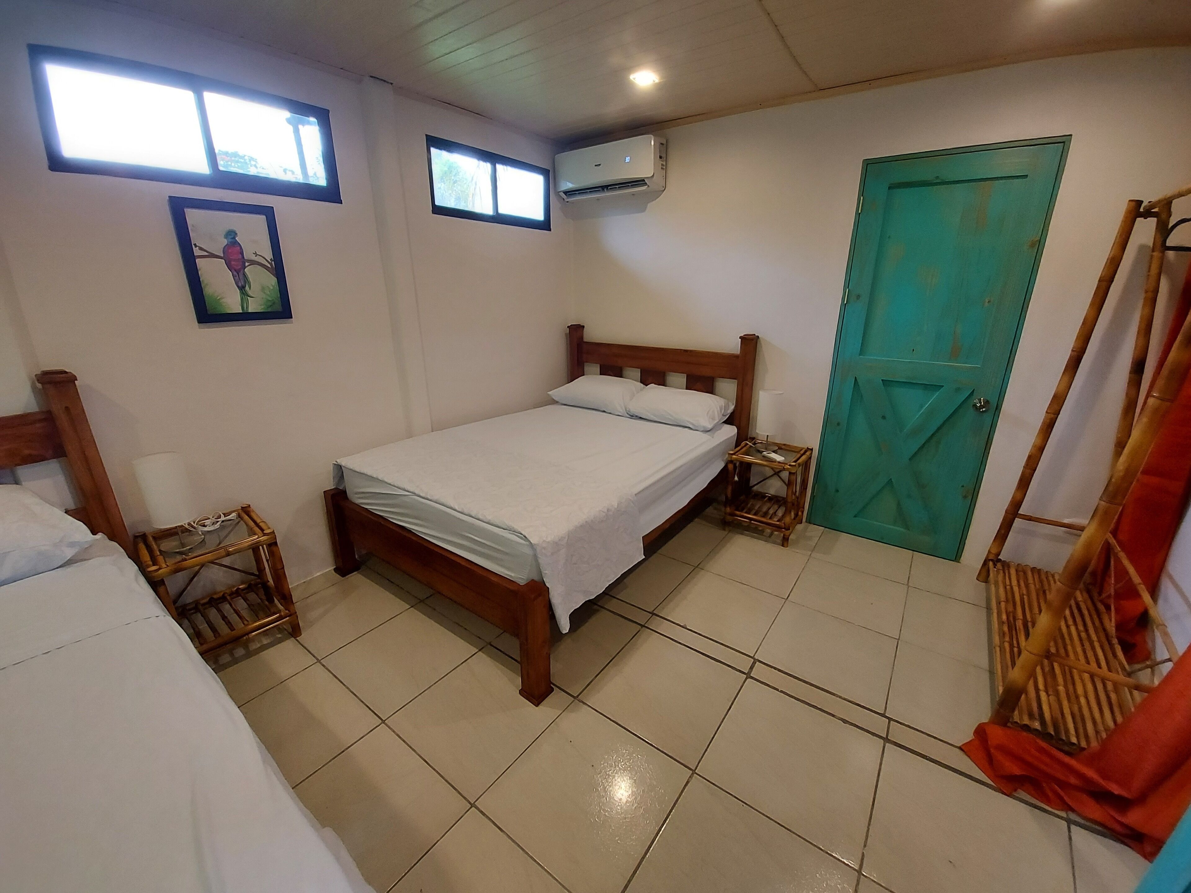 Une chambre à coucher avec un lit en bois, une porte verte et une fenêtre.