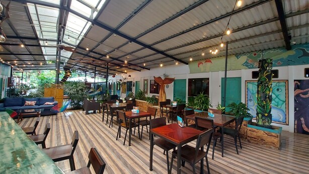 A spacious indoor area with high ceilings, wooden flooring, and multiple seating arrangements including tables and chairs. - Hotel Tucan (Bahía Ballena)