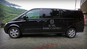 A black van with "HOTEL BIANCOSPINO" and "ACTIVITY" branding parked on a brick pavement. - Hotel Biancospino (Lanzada)