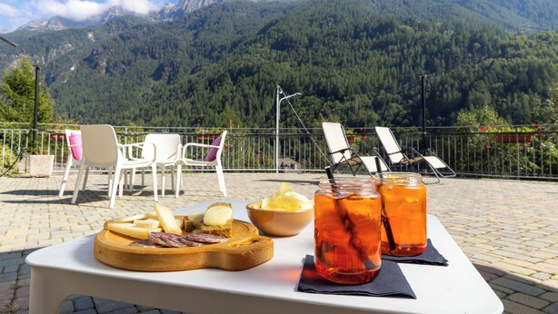 A table with food and drinks on a terrace with mountain views. - Hotel Biancospino (Lanzada)