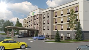 A multi-story hotel with a stone facade, a covered entrance, and a parking area with cars. - Holiday Inn Express & Suites Bryant - Benton Area by IHG (Benton)