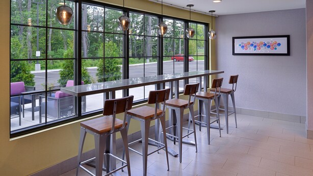 A bar area with high windows, bar stools, and pendant lighting. - Holiday Inn Express & Suites Bryant - Benton Area by IHG (Benton)