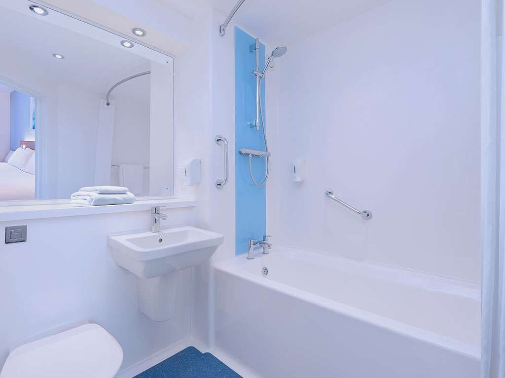 Ein modernes Badezimmer mit Waschbecken, Toilette und Badewanne – alles in Weiß.