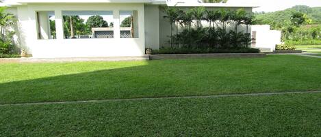 A modern building with a flat roof and a large, well-maintained lawn in front.