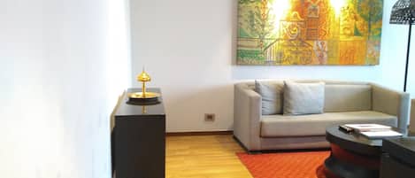A modern living room with a sofa, a coffee table, and a lamp on a stand.