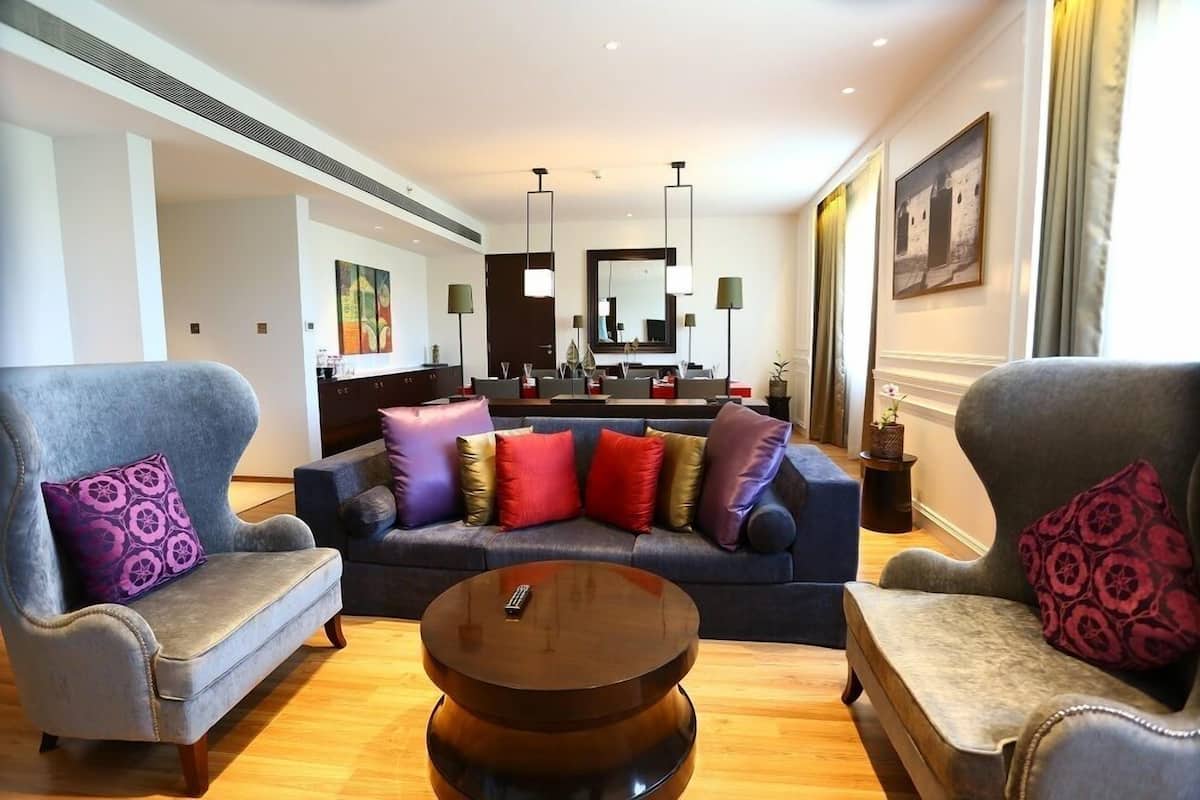 A modern living room with a sofa set, a round coffee table, and a dining area in the background.
