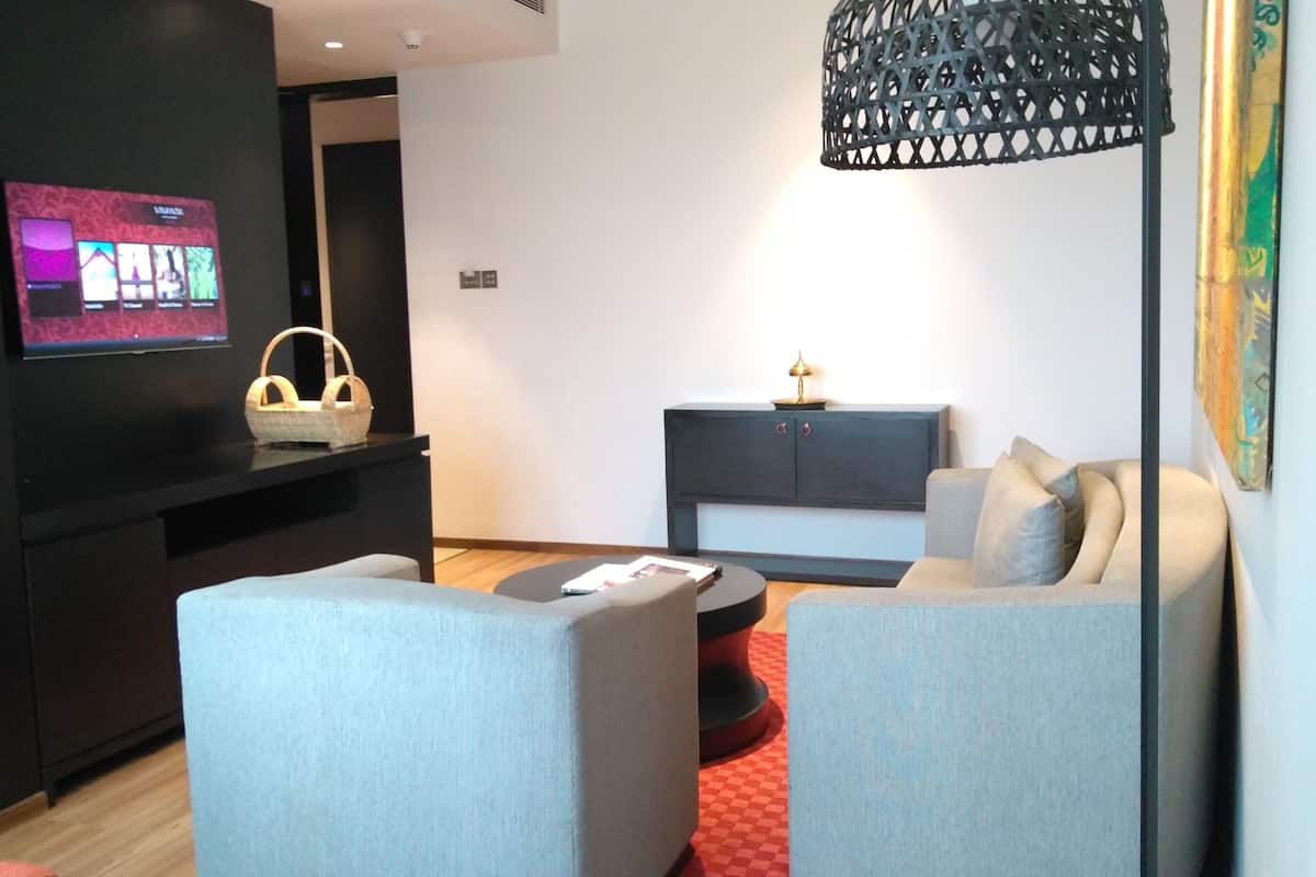 A modern living room with a flat-screen TV, a basket, a sofa, a coffee table, and a decorative lamp.