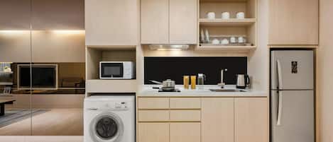 A modern kitchen with built-in appliances, a microwave, a washing machine, and a refrigerator.