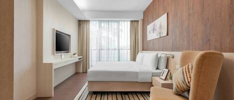 A modern hotel room with a bed, a TV, a wooden accent wall, and a window with curtains.