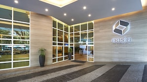 L’extérieur de l’hôtel Oasia Suites Kuala Lumpur se distingue par son design moderne, avec de grandes fenêtres en verre et un logo bien visible.
