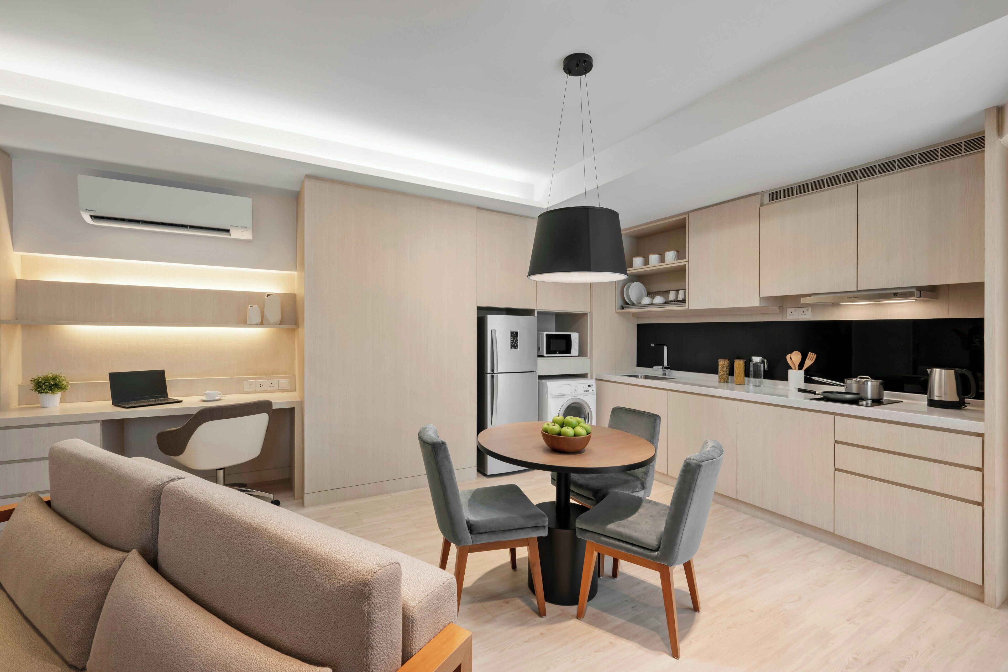 Una cocina moderna con electrodomésticos integrados, una zona de comedor con una mesa redonda y sillas, y un sofá en la sala de estar.