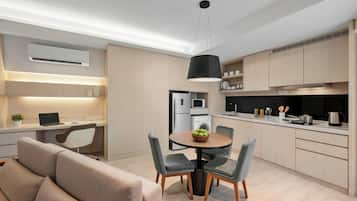 A modern kitchen with built-in appliances, a dining area with a round table and chairs, and a sofa in the living area.