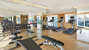 Une salle de sport moderne équipée de tapis de course, d’haltères et de bancs.