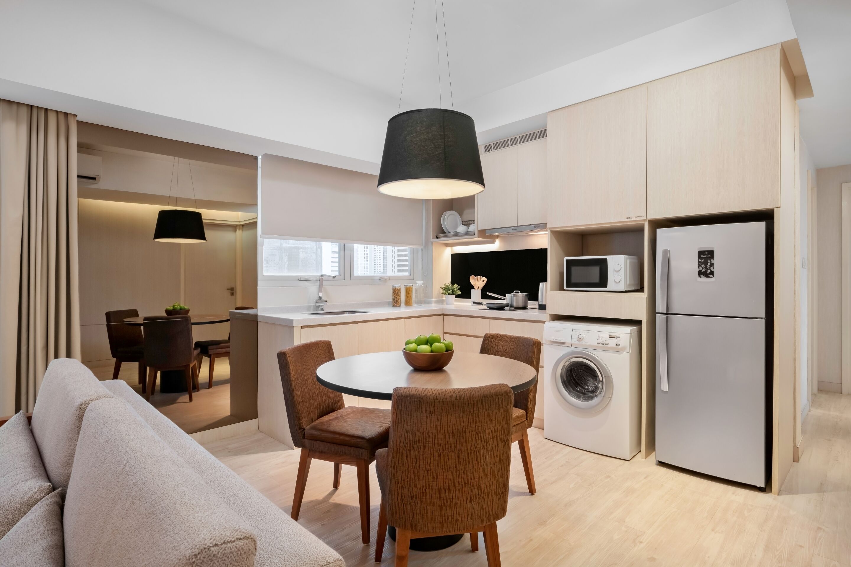 A modern kitchen with a dining area, a washing machine, and a refrigerator.