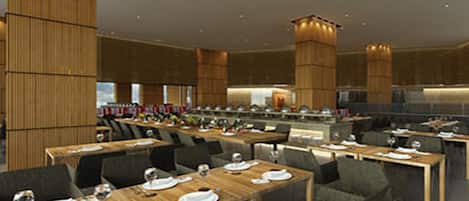 A modern dining area with multiple tables and chairs, wooden paneling on the walls, and a central light fixture.