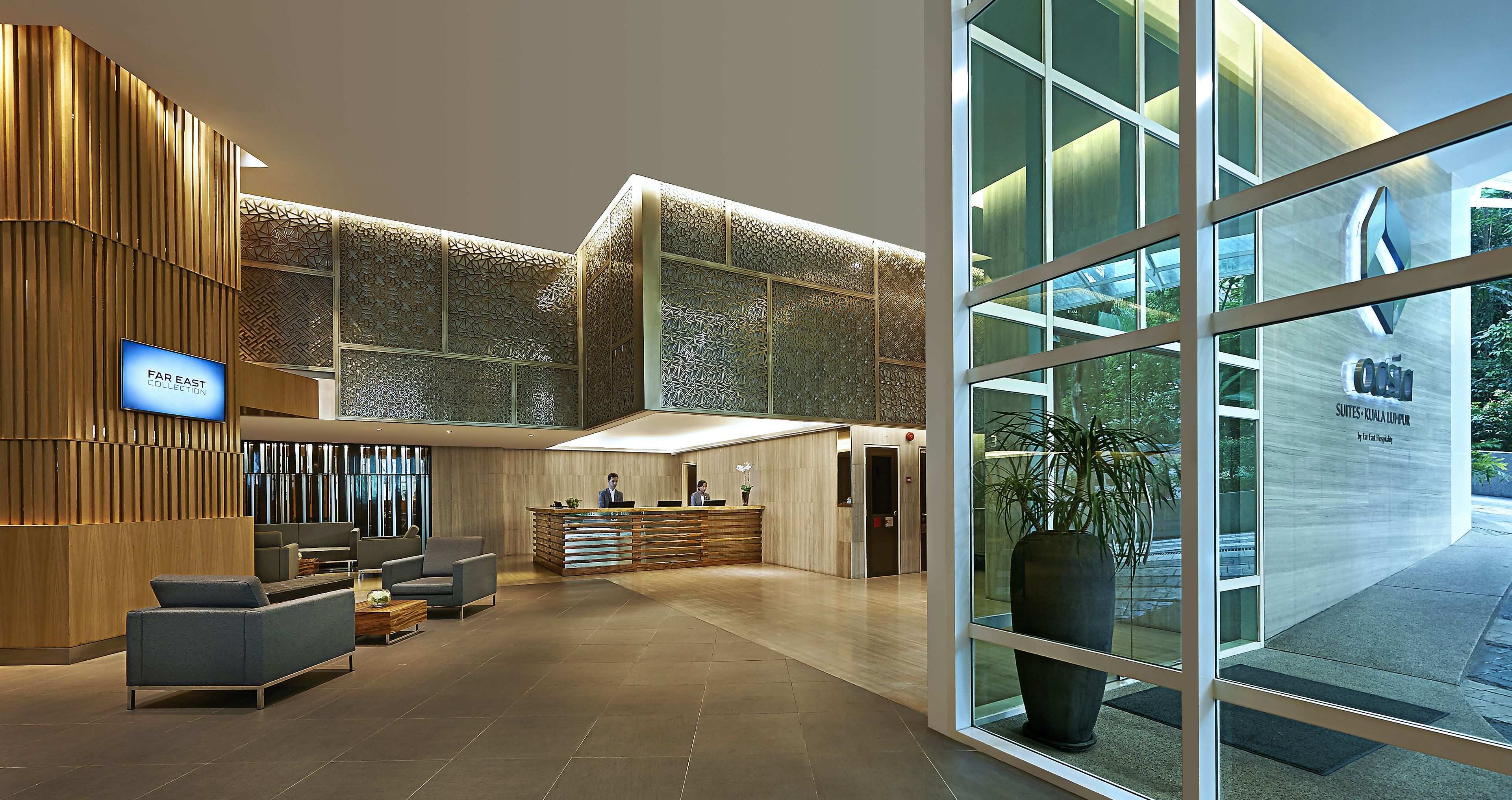 A modern hotel lobby with a reception desk, seating area, and large windows offering views of the outdoors.