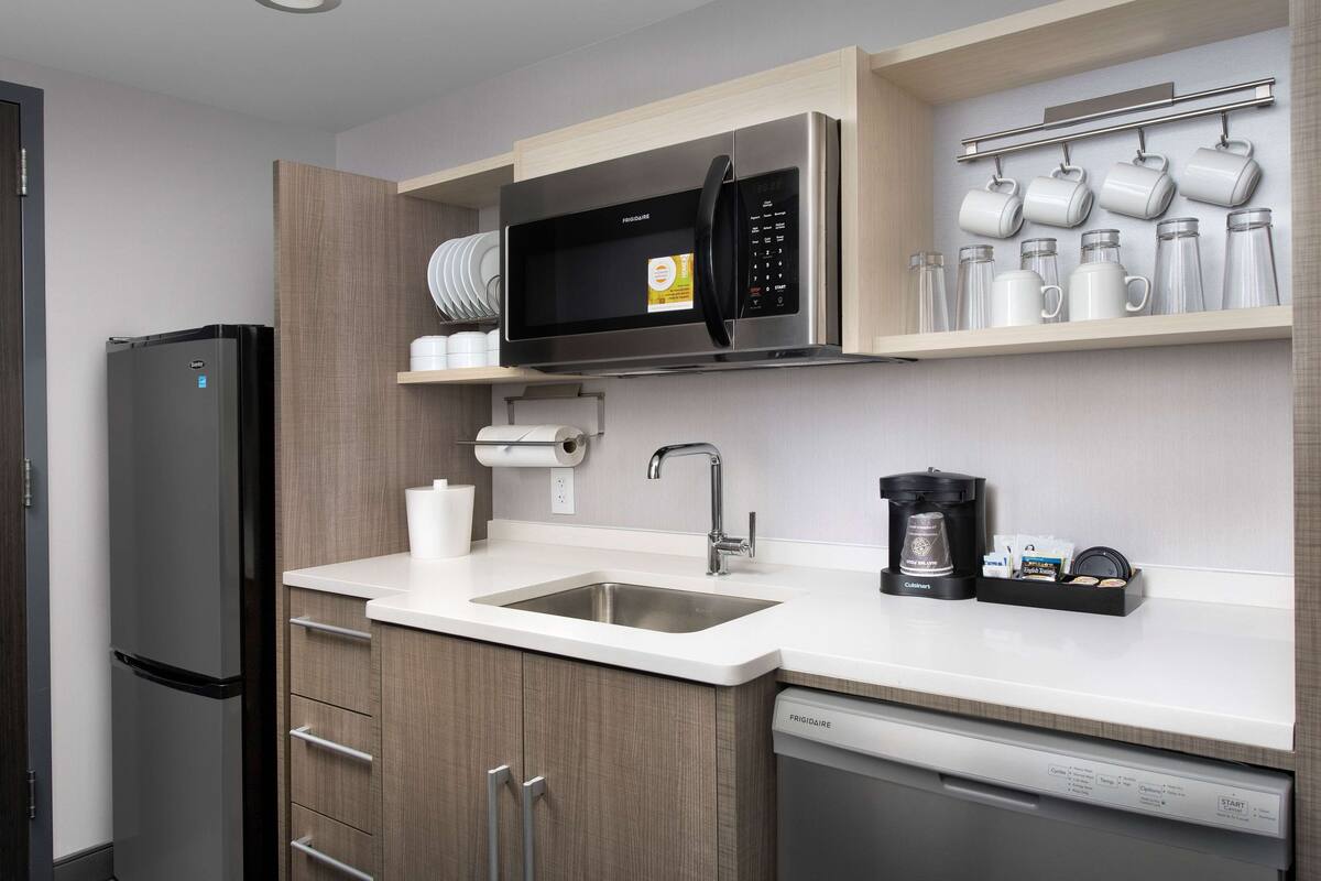 A modern kitchen with a stainless steel refrigerator, a microwave, a coffee maker, and a dishwasher.